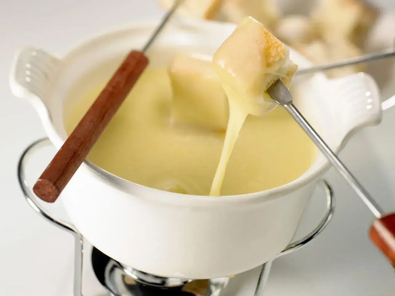 Un pezzo di pane viene intinto in una cremosa fonduta di stracchino, che cola filante.