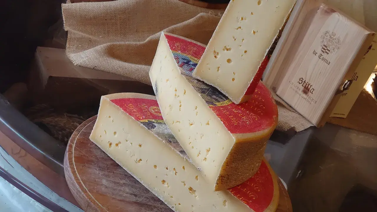 Fette di formaggio stagionato, con buchi, su un tagliere. Attenzione, la scamorza fa ingrassare!