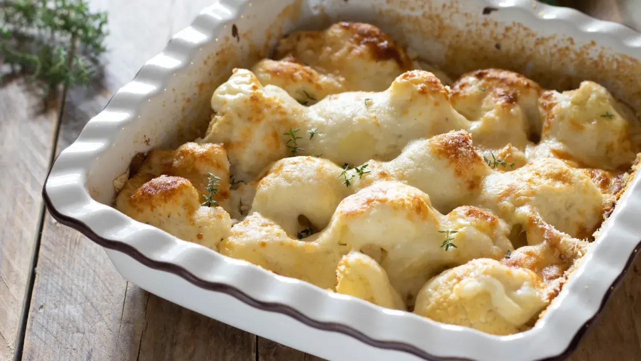 Cavolfiore al forno con pangrattato e formaggio filante, guarnito con rametti di timo fresco.