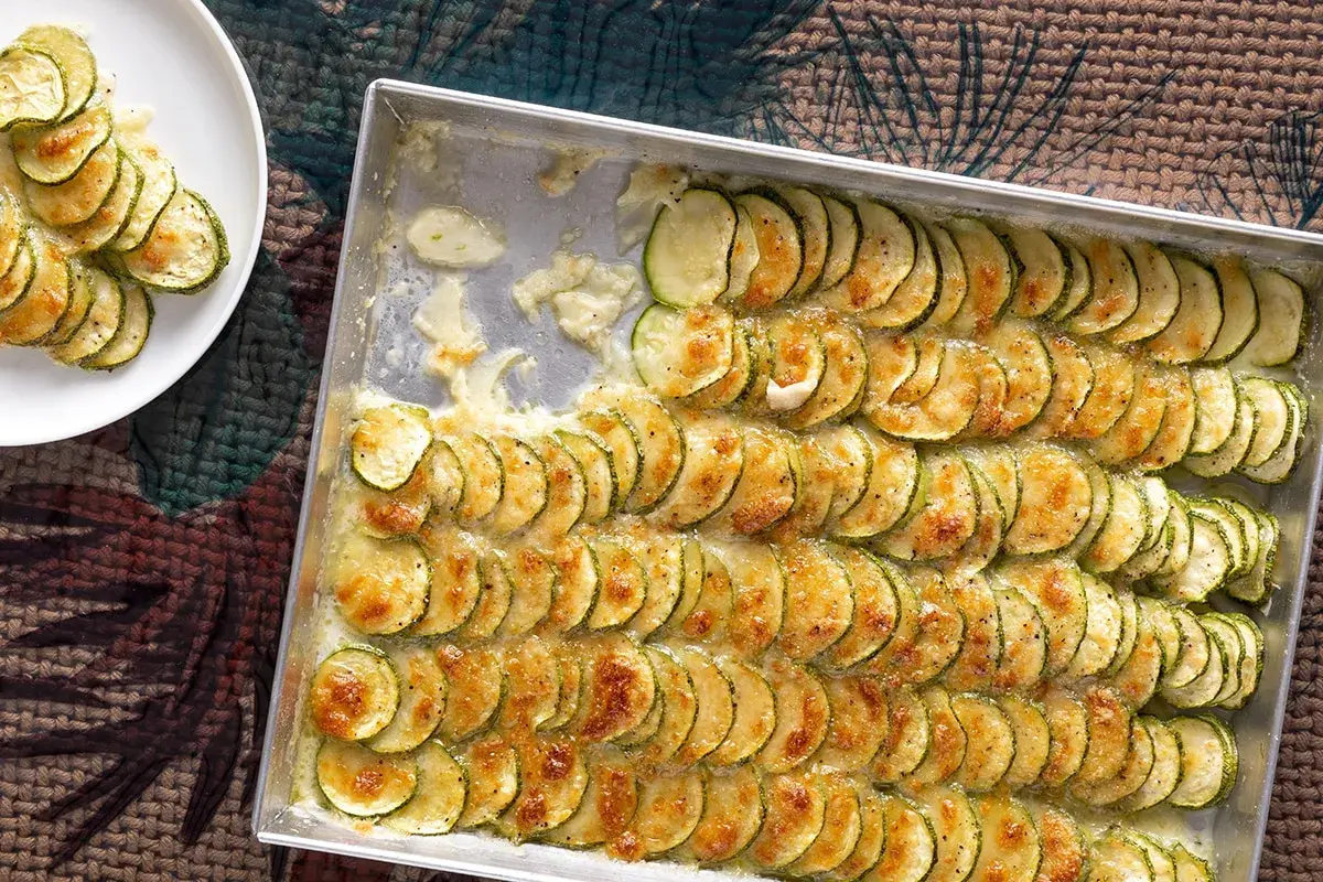 Zucchine al forno con mozzarella, disposte a raggiera in una teglia, dorate e filanti. Un piatto semplice e gustoso.