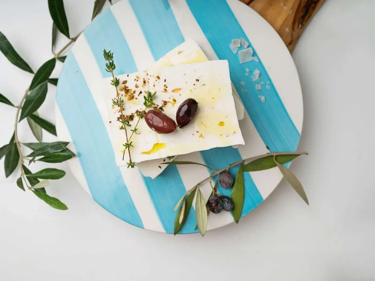 Blocchi di feta conditi con erbe e olive, pronti per essere gustati. Un'ispirazione su come fare la feta in casa.