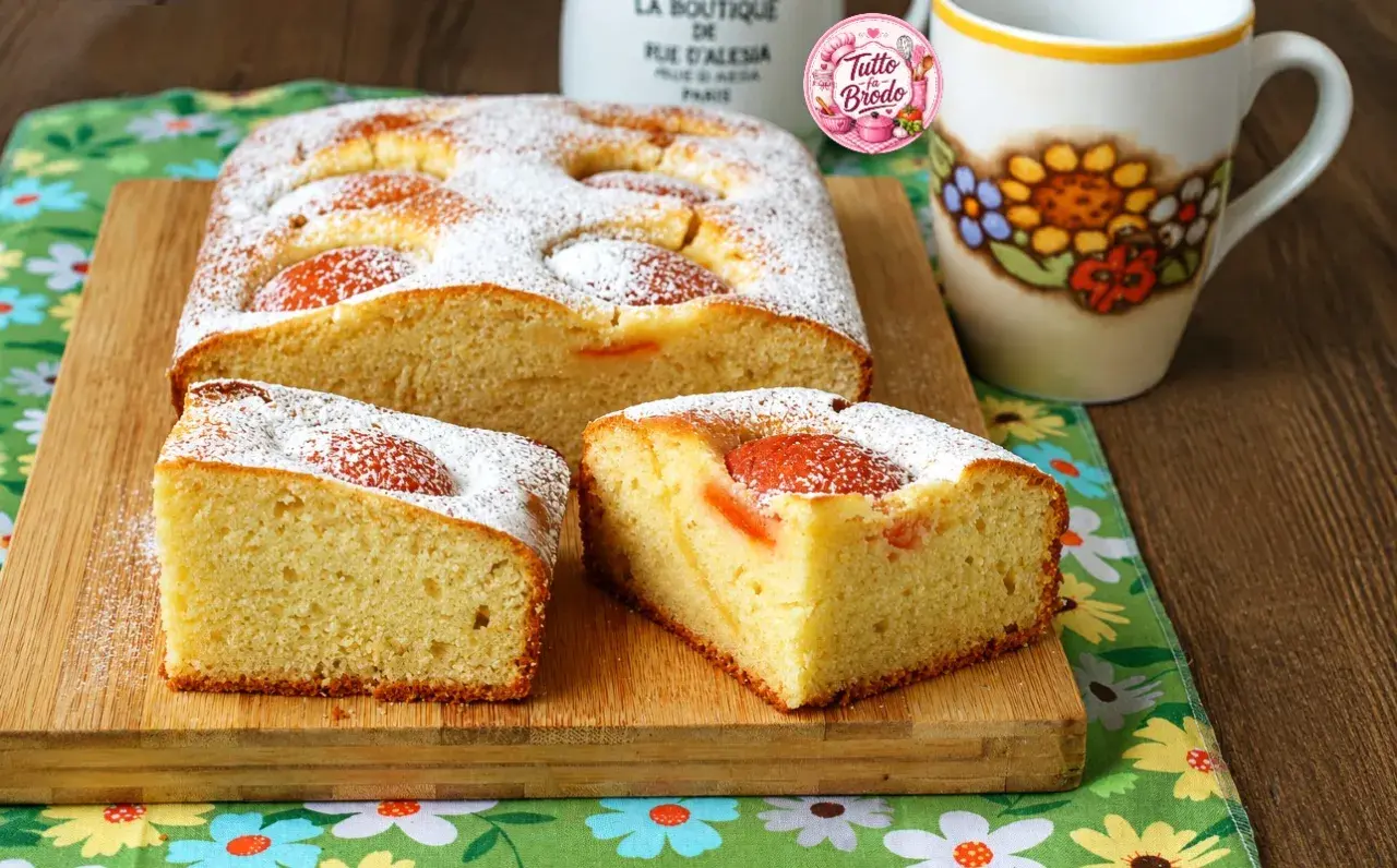 Torta albicocche e yogurt soffice, cosparsa di zucchero a velo, con pezzi di albicocca visibili. Perfetta per la colazione.