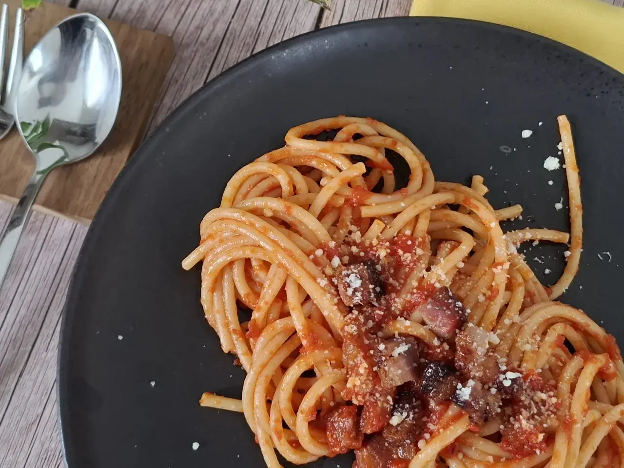 Un piatto di pasta all'amatriciana fumante, con guanciale croccante e pecorino grattugiato, pronto per essere gustato.