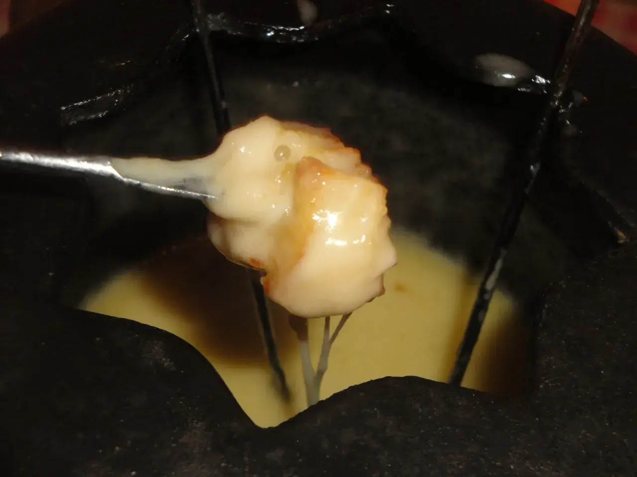 Un pezzo di pane intinto nella fonduta savoyarde ricetta, filante e dorato, pronto per essere gustato.