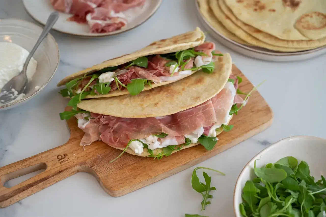 Piadina ripiena di prosciutto crudo, rucola e squacquerone, un formaggio grasso che rende tutto più goloso.