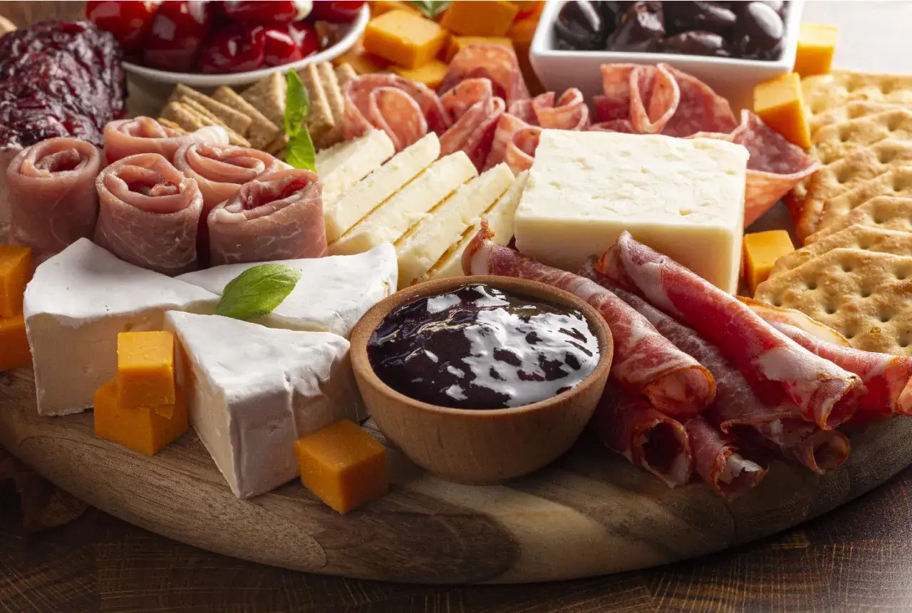 Tagliere ricco con formaggi, salumi, cracker e una ciotolina di composta di fichi per formaggi, perfetta per un aperitivo.