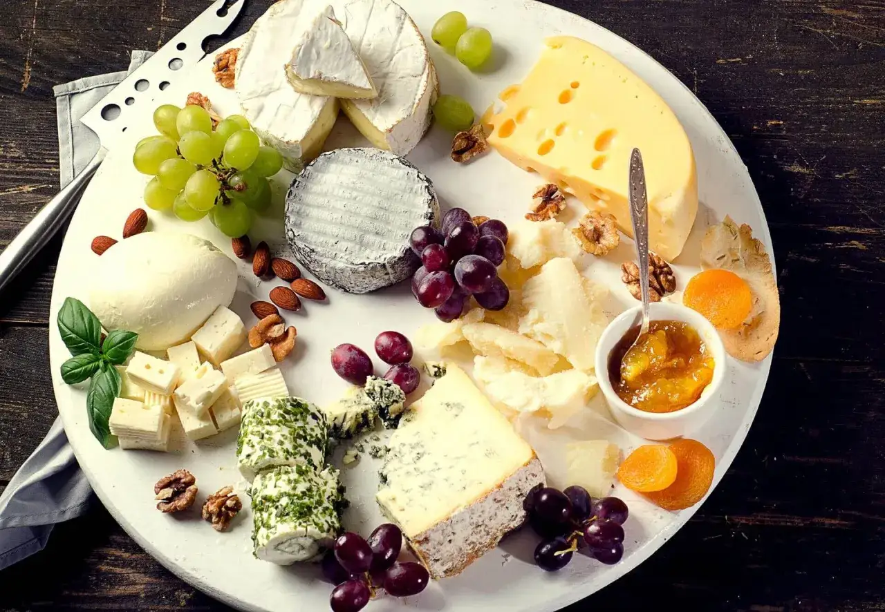 Un ricco assortimento per degustazioni formaggi: brie, blu, caprino, emmental, parmigiano, accompagnati da uva, noci, mandorle e confettura.