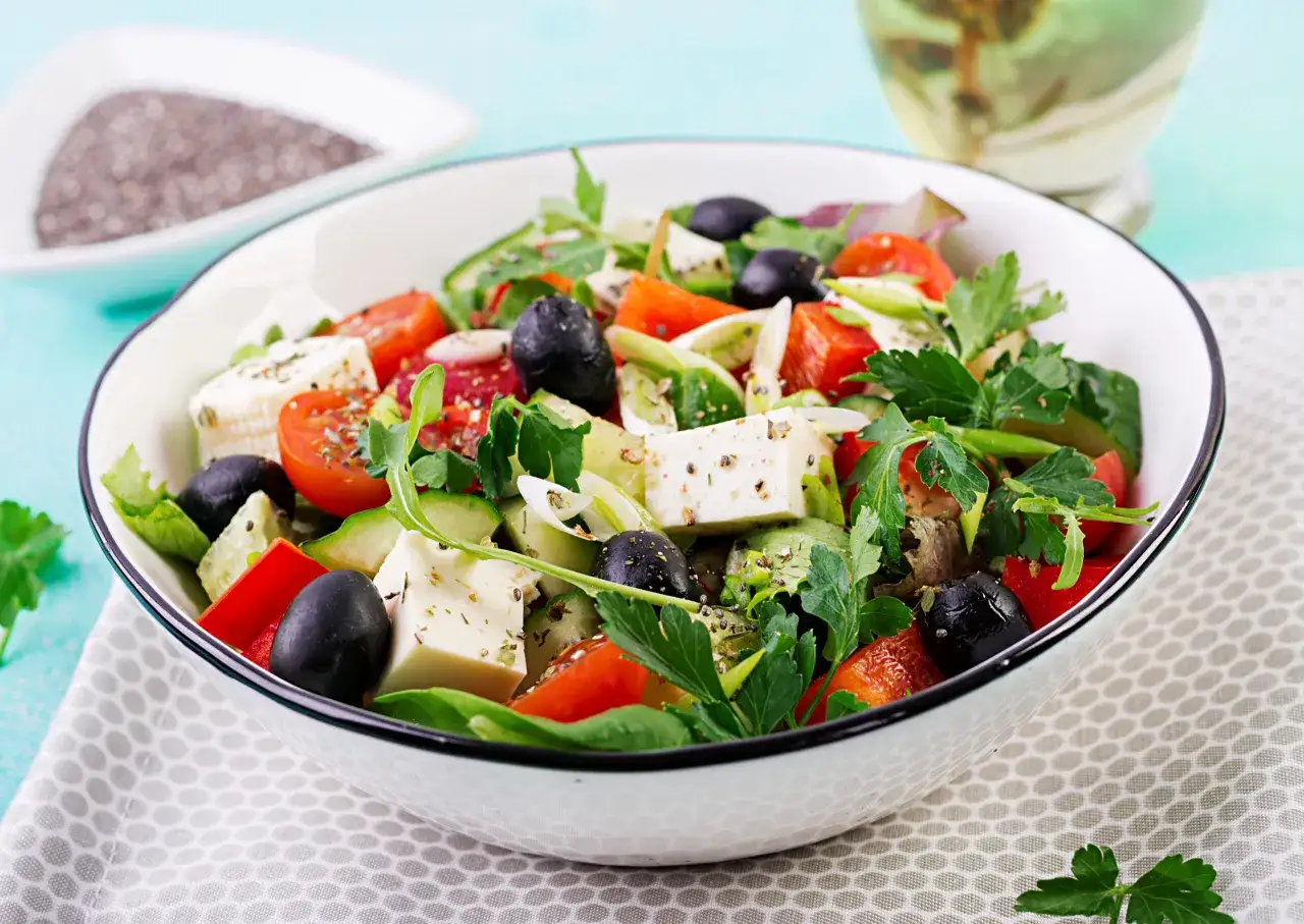 Insalata greca con feta, pomodori, olive nere, cetrioli e peperoni rossi. Un'idea fresca per le tue ricette con feta greca.