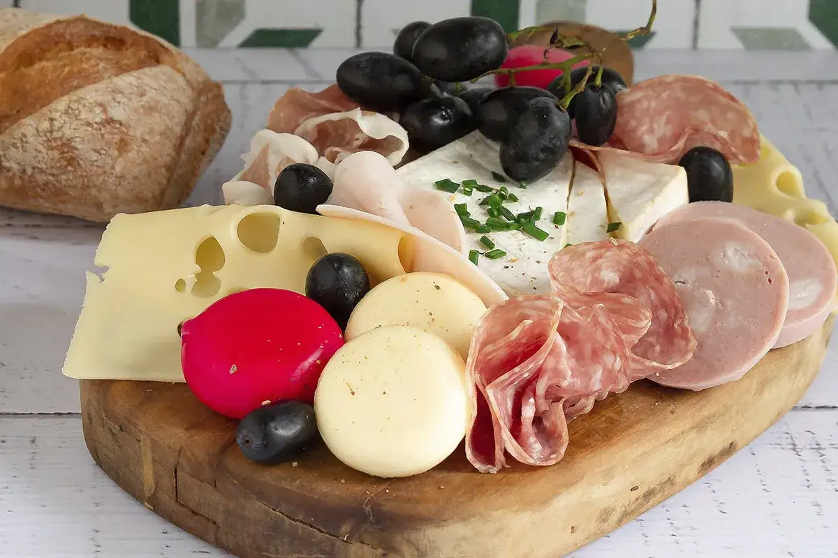 Tagliere di salumi e formaggi con uva, olive e pane. Perfetto per idee tagliere di salumi e aperitivi.