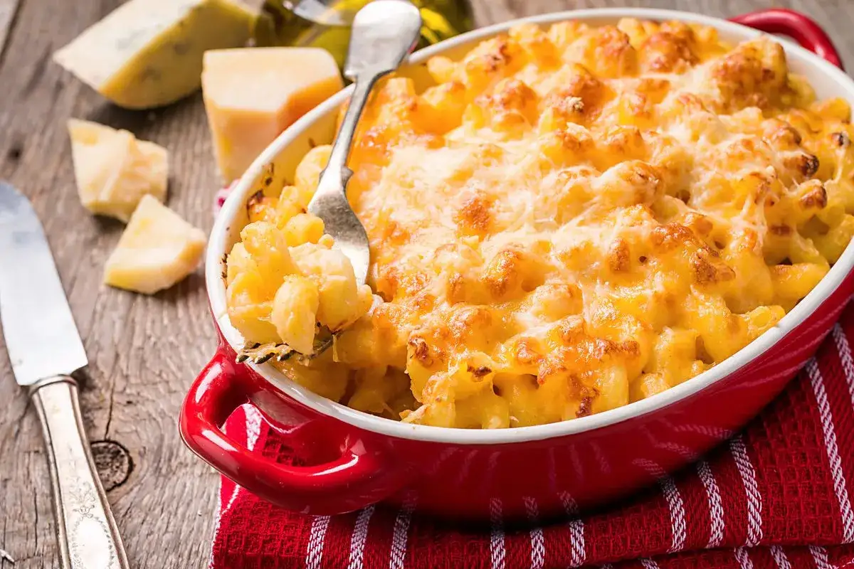 Mac and cheese filante in una teglia rossa, con formaggio fuso e croccante. Perfetto per una cena confortante.