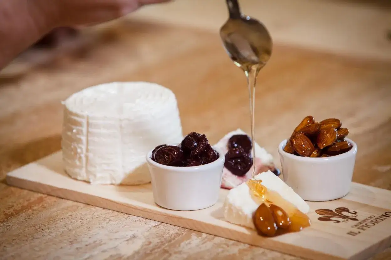 Un piatto di formaggio pecorino con confettura di ciliegie, mandorle caramellate e un filo di miele dorato.