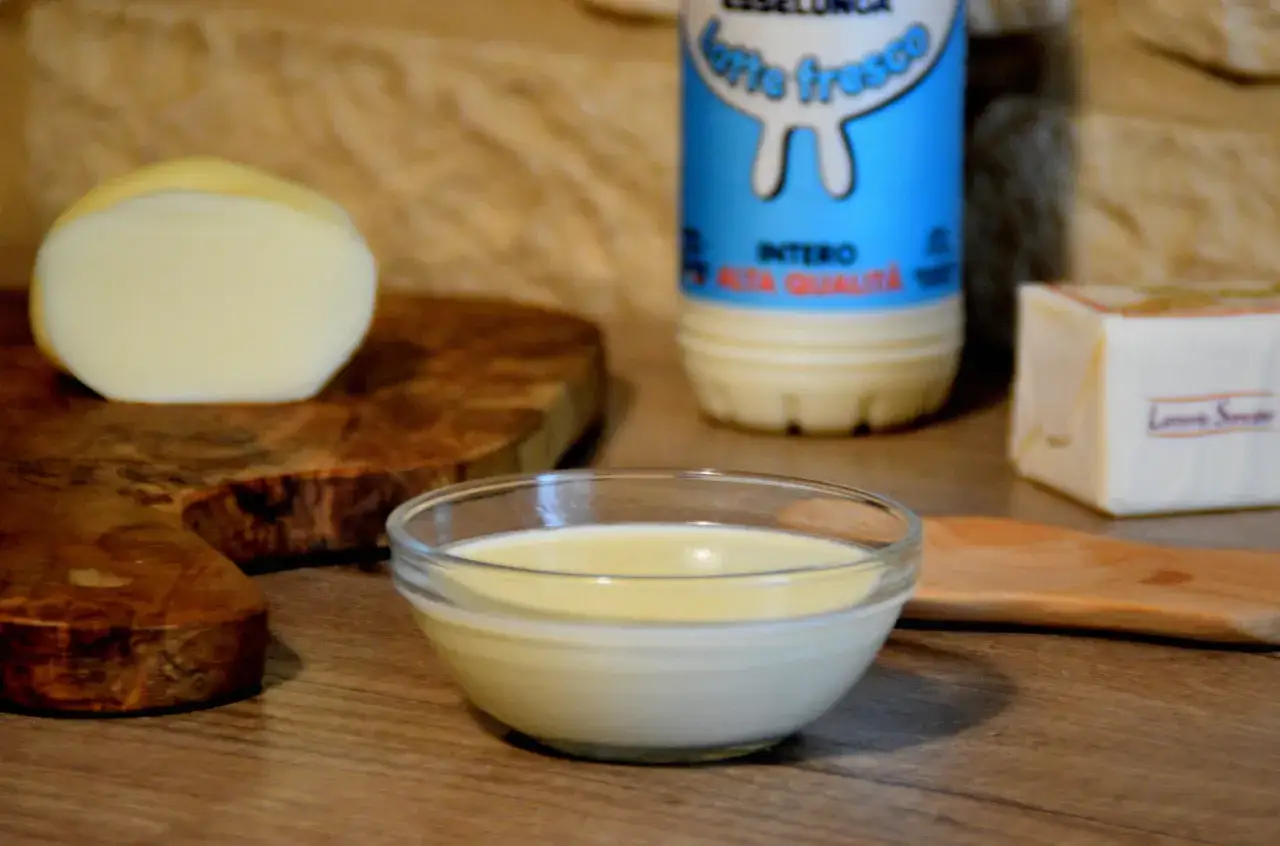 Una ciotola di fonduta di scamorza affumicata, con latte e burro sullo sfondo, pronta per essere gustata.