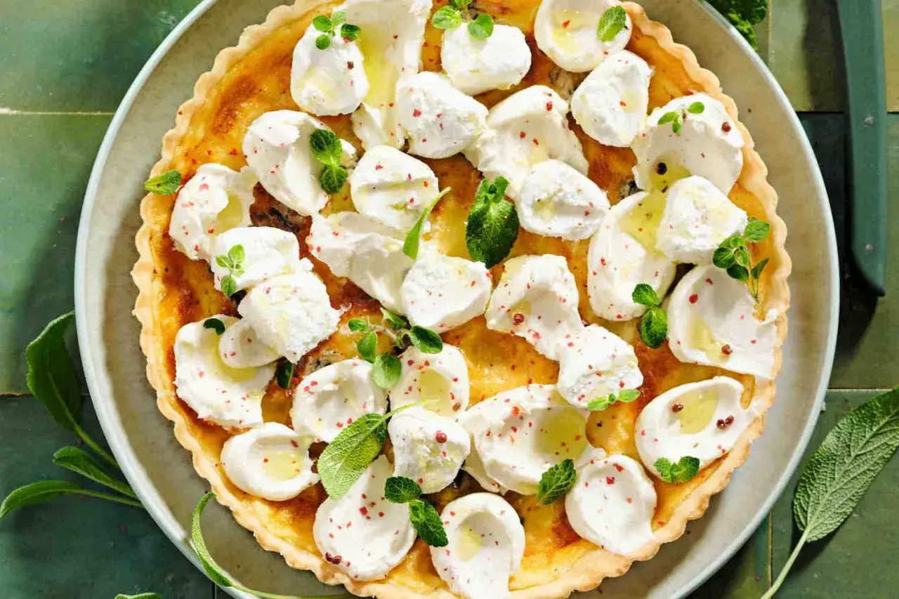 Torta salata con formaggi avanzati, guarnita con erbe fresche e pepe rosa. Un'idea gustosa per non sprecare.