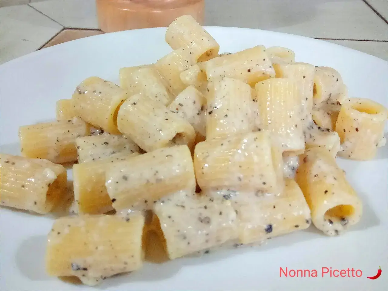 Rigatoni conditi con una cremosa salsa cacio e pepe, un classico piatto italiano.