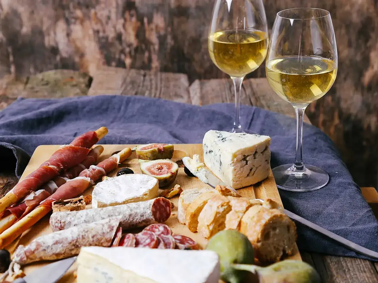 Un tagliere con salumi, formaggi, fichi e pane, perfetto per imparare come disporre i salumi nel piatto per un aperitivo invitante.