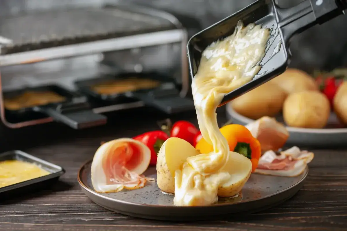 Formaggio fuso che cola su patate e salumi, un modo delizioso per imparare come fondere il formaggio.