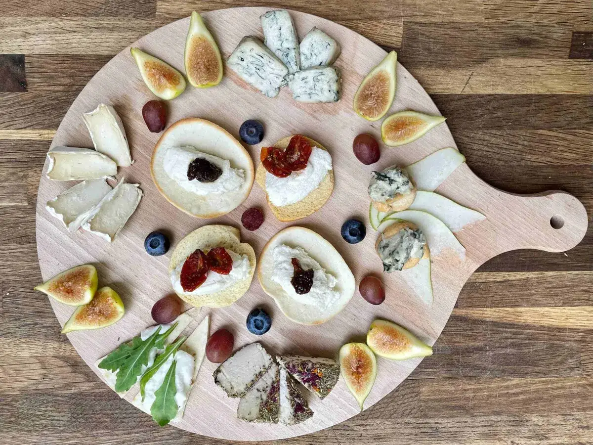 Tagliere con formaggio vegano, fichi, uva, mirtilli e cracker.
