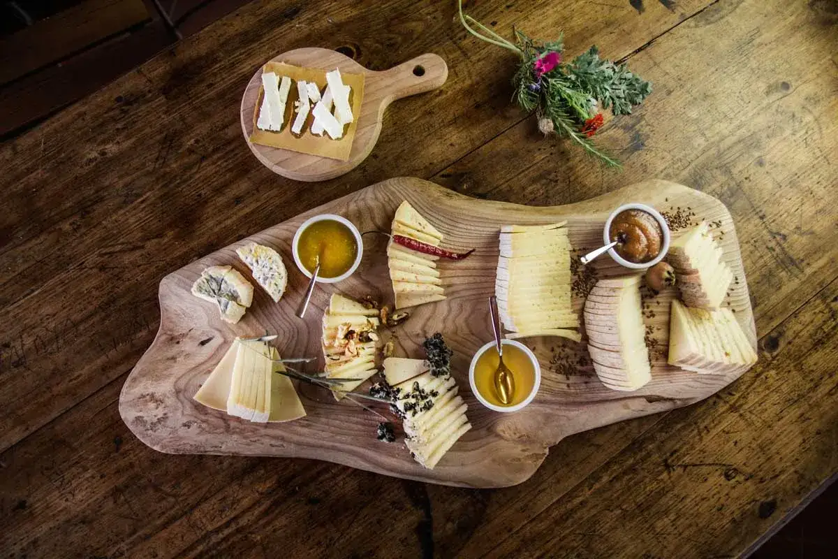 Un ricco assortimento di formaggi, miele e confetture per perfette degustazioni formaggi su un tagliere rustico.