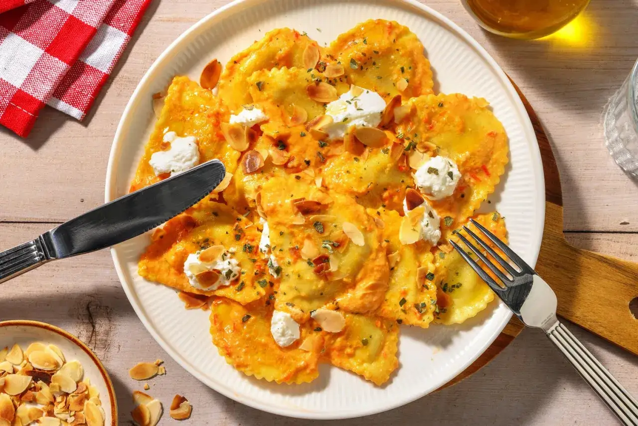 Ravioli con salsa arancione, guarniti con ricotta fresca e mandorle. Un'idea su cosa abbinare alla ricotta fresca per un piatto gustoso.