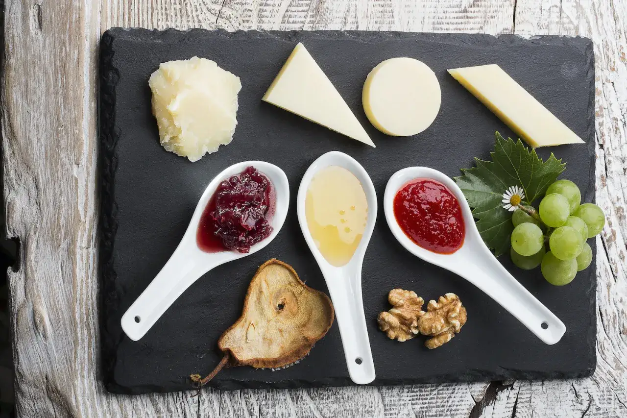 Assortimento di formaggi con marmellata per formaggi, miele, uva e noci.
