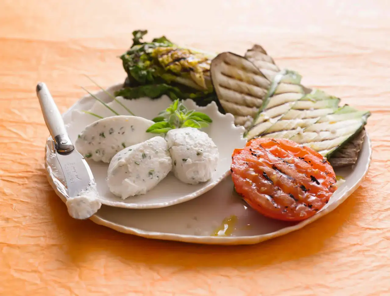Formaggio fresco con erbe e verdure grigliate: un piatto che celebra gli abbinamenti formaggi e verdure, con pomodoro, melanzane e lattuga.