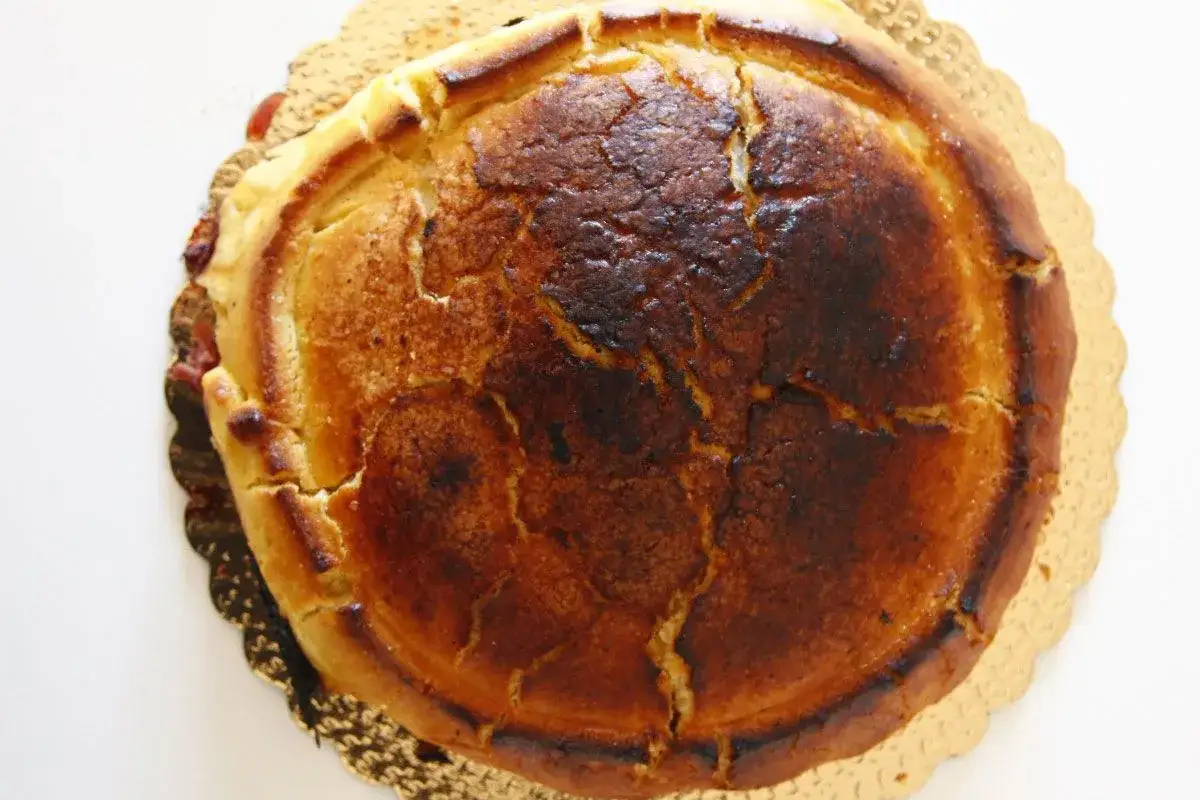 Crostata ricotta e visciole dorata e leggermente bruciacchiata, con la crosta crepata che promette un ripieno delizioso.