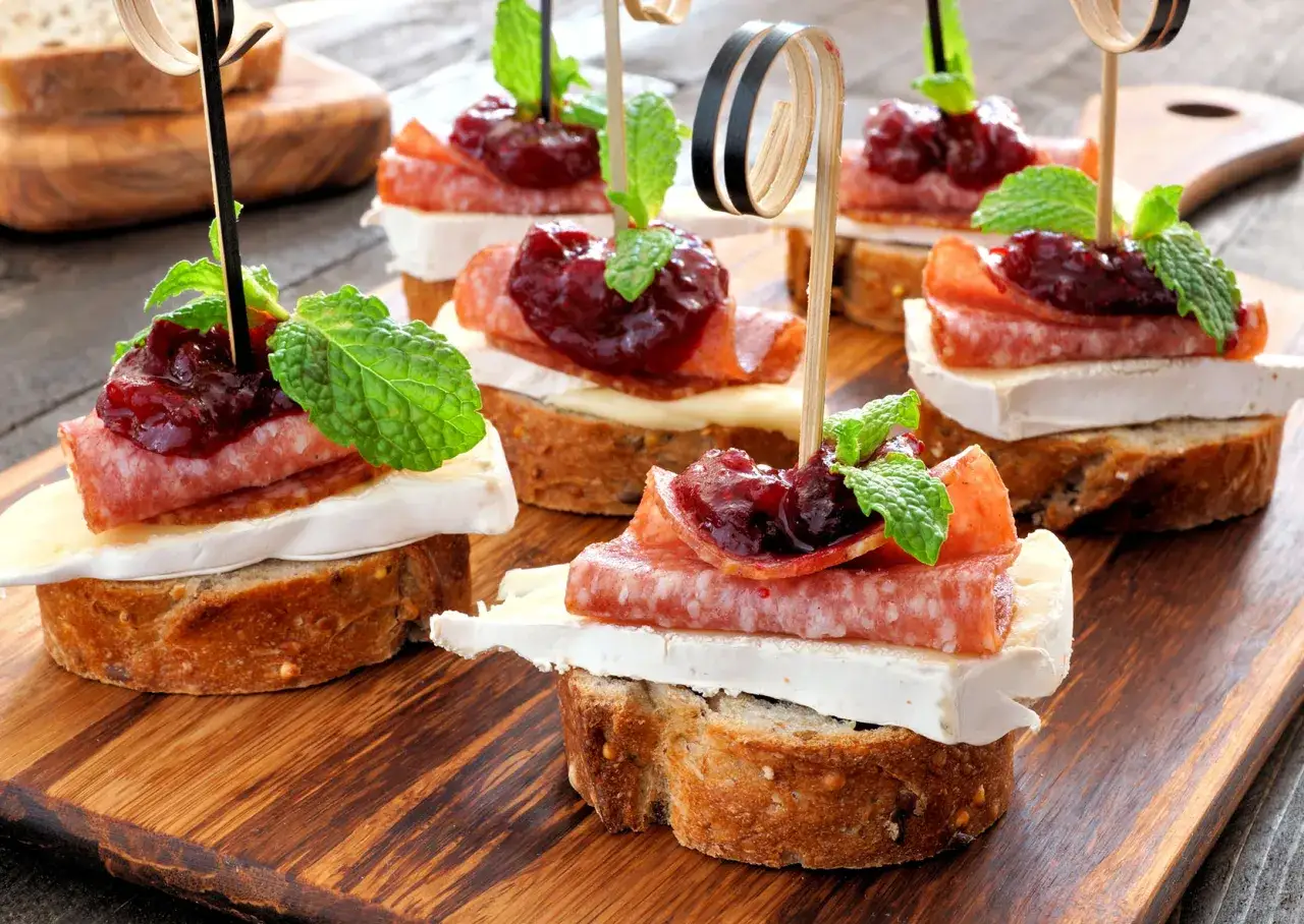 Deliziosi crostini con salame, il brie &egrave; un formaggio grasso, marmellata di frutti rossi e menta fresca.